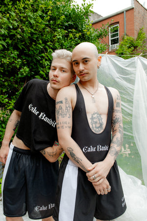 Two people wearing matching black outfits with 'Cake Bandit' branding outdoors.