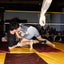 Two wrestlers in a match inside a boxing ring with a referee and audience watching. One is wearing the no. 1 singles