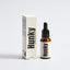 An amber glass dropper bottle of Hunky Soothing Beard Oil next to its cream-colored cardboard box, both featuring bold black typography, set against a clean light gray background.
